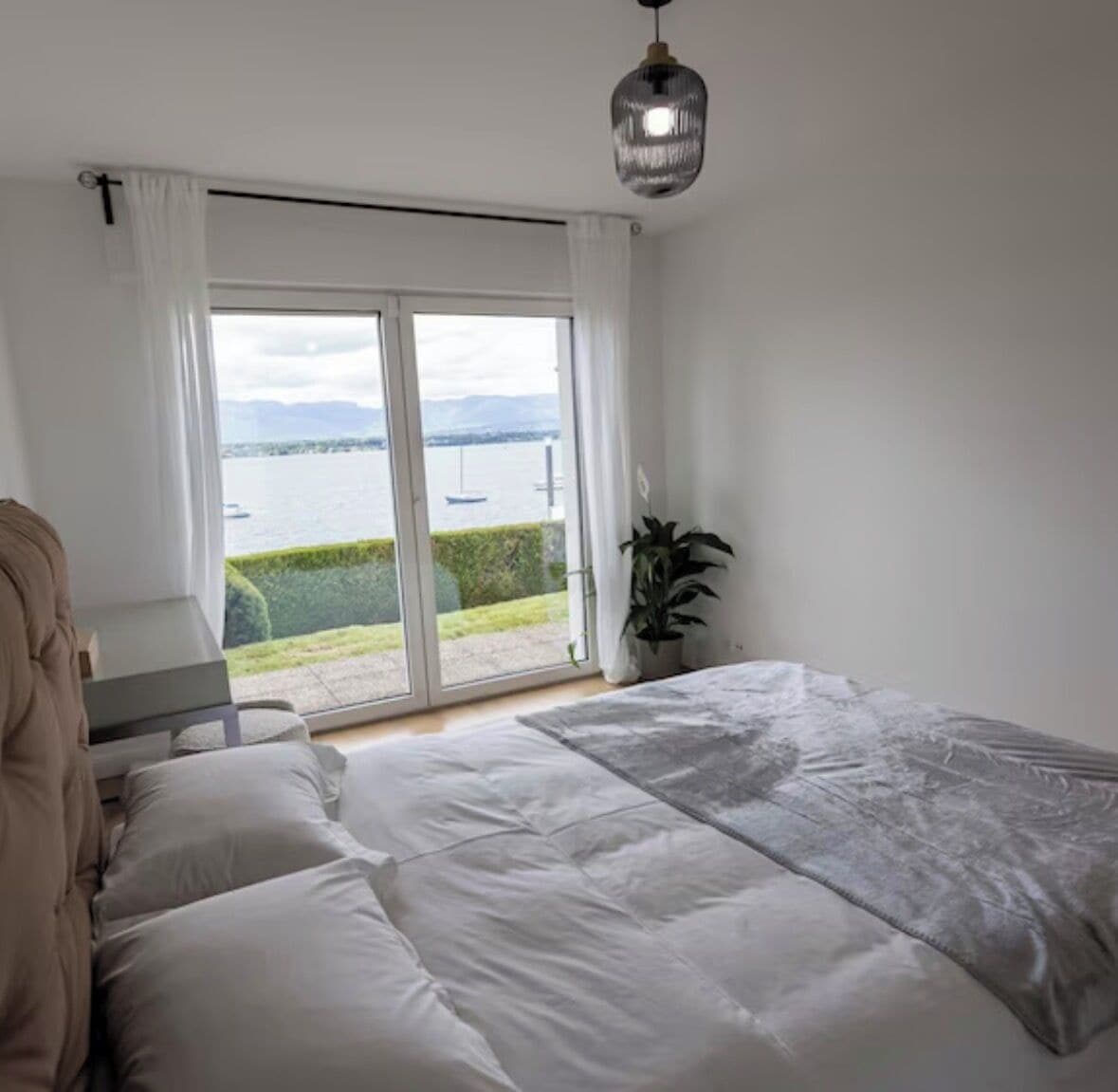 Ein Schlafzimmer mit Bett, Schreibtisch, Topfpflanze und Meerblick.