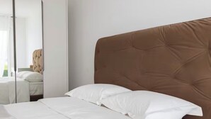 A bedroom with a bed, white bedding, a brown headboard, and a mirror. - Elite Villa Geneva (Cologny)