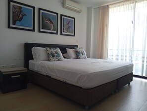 A bedroom with a bed, nightstands, a wall-mounted air conditioner, and framed bird paintings.
