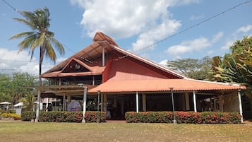 A building with a red roof, a covered porch, and a garden with red flowers.