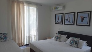 A hotel room with a large bed, a smaller bed, a window with sheer curtains, and three framed pictures on the wall. - Hotel Saman Del Rio (Yopal)