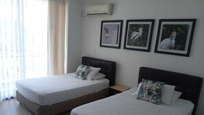 Two single beds with headboards, a nightstand, and a wall-mounted air conditioner. - Hotel Saman Del Rio (Yopal)