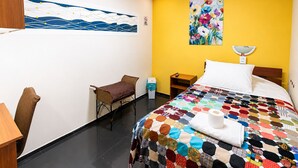 Ein Hotelzimmer mit Bett, Sessel, Nachttisch, einem Bild und einem Verbotsschild für Fahrzeuge.
