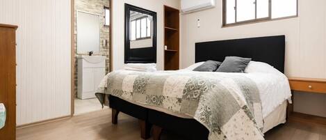Un dormitorio con cama, armario, espejo y ventana.