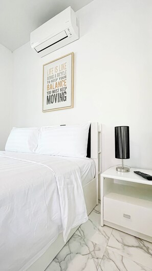 Ein modernes, minimalistisches Schlafzimmer mit einem Bett, einem Nachttisch mit Lampe und einer Klimaanlage.