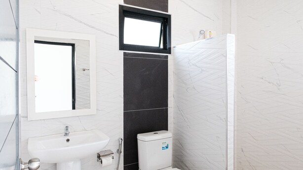 A modern bathroom with a white sink, mirror, toilet, and shower. - Z-beach Resort (Pranburi)