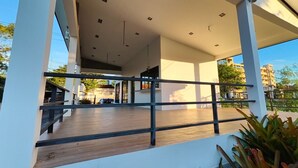 A modern building with a covered outdoor area, a wooden deck, and a metal railing. - Z-beach Resort (Pranburi)