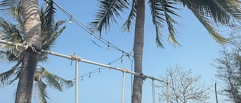 A beach with palm trees, a swing set, and a clear view of the ocean.