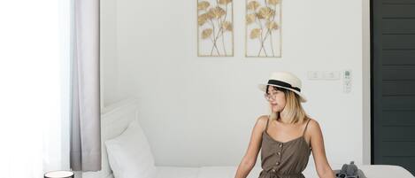 A room with a bed, a standing lamp, and a wall-mounted air conditioner.