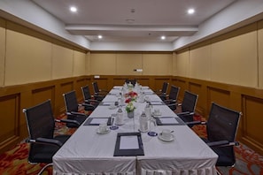 Ein Konferenzraum mit einem langen Tisch, Stühlen und einer floralen Tischdekoration.