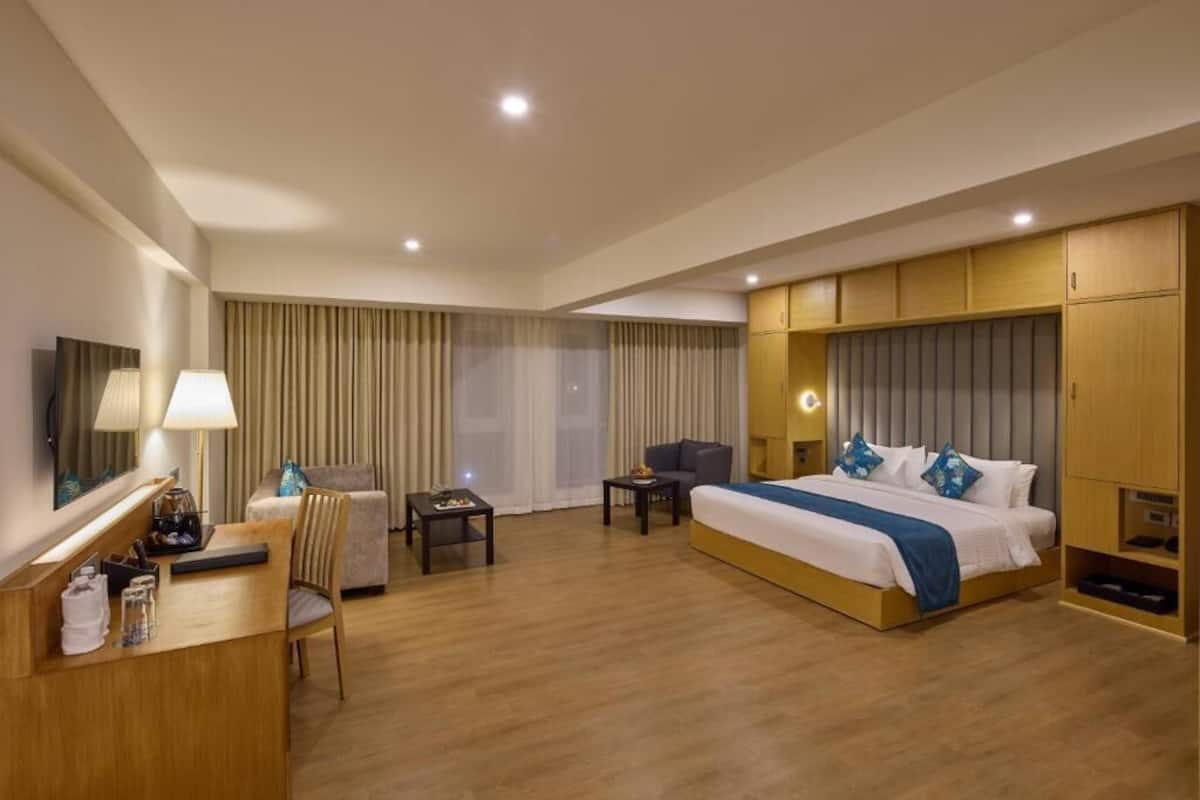 A hotel room with a bed, a desk, a chair, a TV, and a wardrobe.