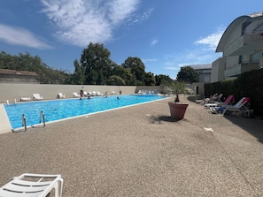 A swimming pool with lounge chairs and a potted plant. - Escape to Les Minimes – Pool, Balcony & Private Parking (La Rochelle)