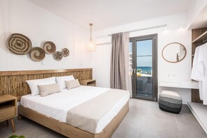 A modern bedroom with a wooden headboard, a large bed, bedside tables, a round mirror, and a view of the sea through a sliding door. - Nefeli's Apartment with Sea View and Private Balcony (Kardamaina)