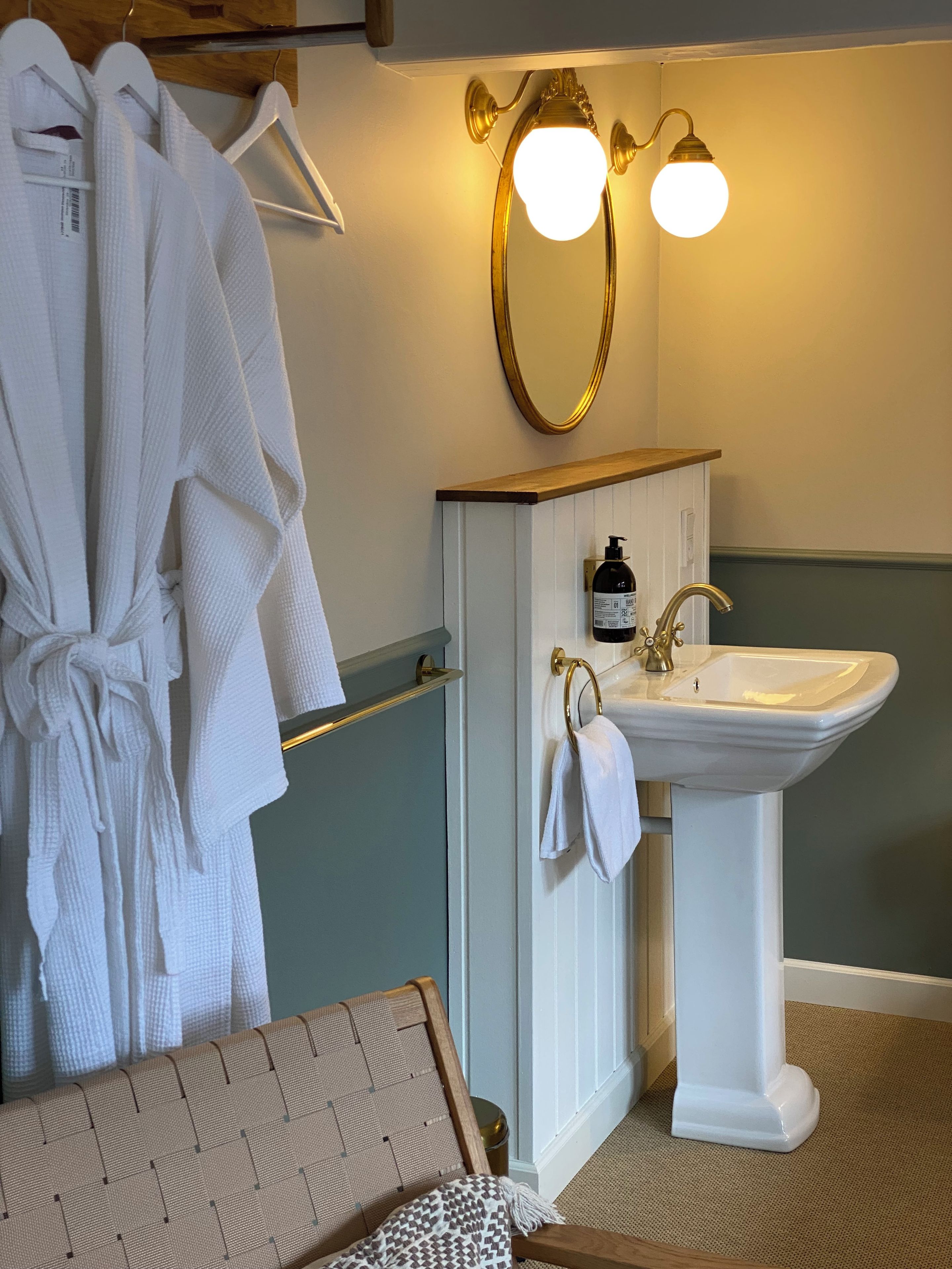 Ein Badezimmer mit einem weißen Waschbecken, goldenen Armaturen und einem Spiegel darüber.