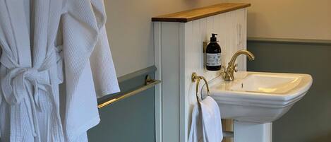 A bathroom with a white sink, gold fixtures, and a mirror above it.
