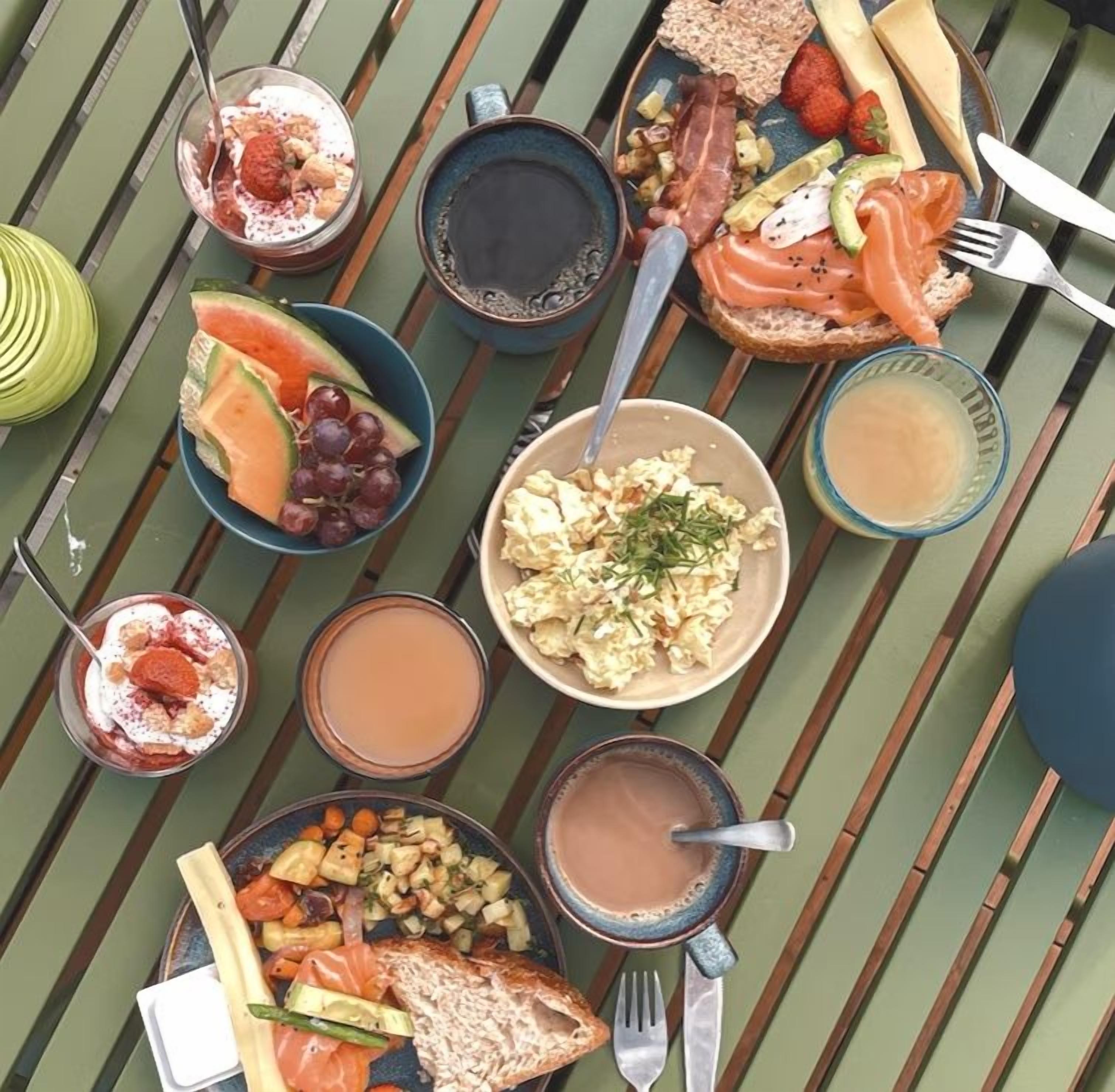 Une variété d’aliments et de boissons pour le petit-déjeuner, disposés sur une table en bois.