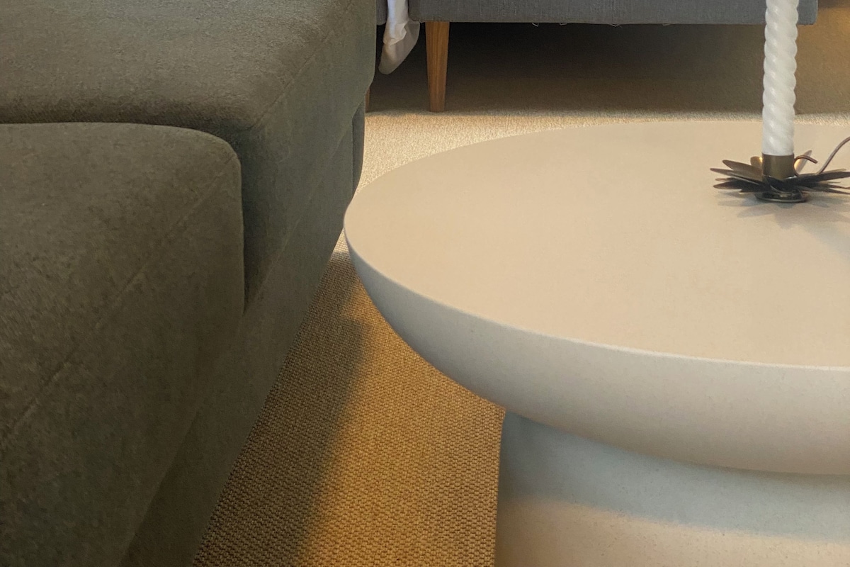 A hotel room with a bed, a sofa, a bedside table, and a lamp.