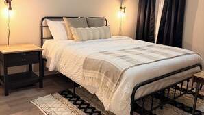 A modern bedroom with a metal bed frame, a patterned rug, and a wall-mounted light fixture. - The House Mcallen 3bdroom Pool (McAllen)