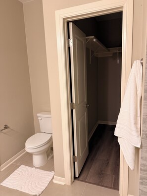 Ein Badezimmer mit Toilette, einem weißen Handtuch an der Wand und einem weißen Teppich auf dem Boden.