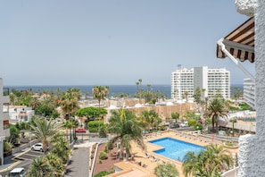 Un complexe hôtelier doté d’une piscine, de palmiers et offrant une vue sur l’océan.