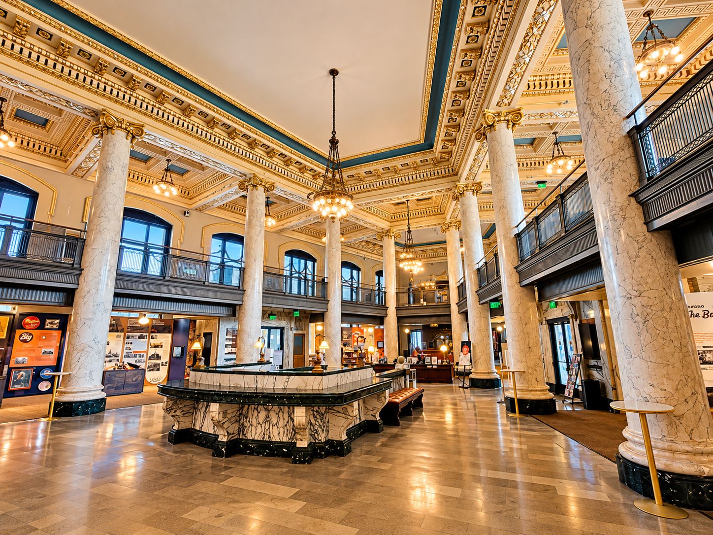 Un hall espacioso con columnas de mármol, una fuente central y un entresuelo con balcones.
