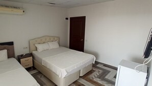 Une chambre avec deux lits, une table de chevet, une armoire, un climatiseur et un téléviseur.