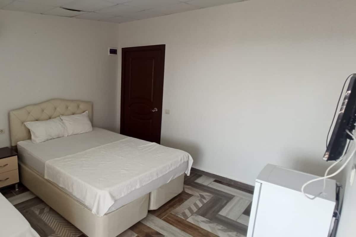 Un dormitorio con dos camas, una mesita de noche, un armario, aire acondicionado y una televisión.