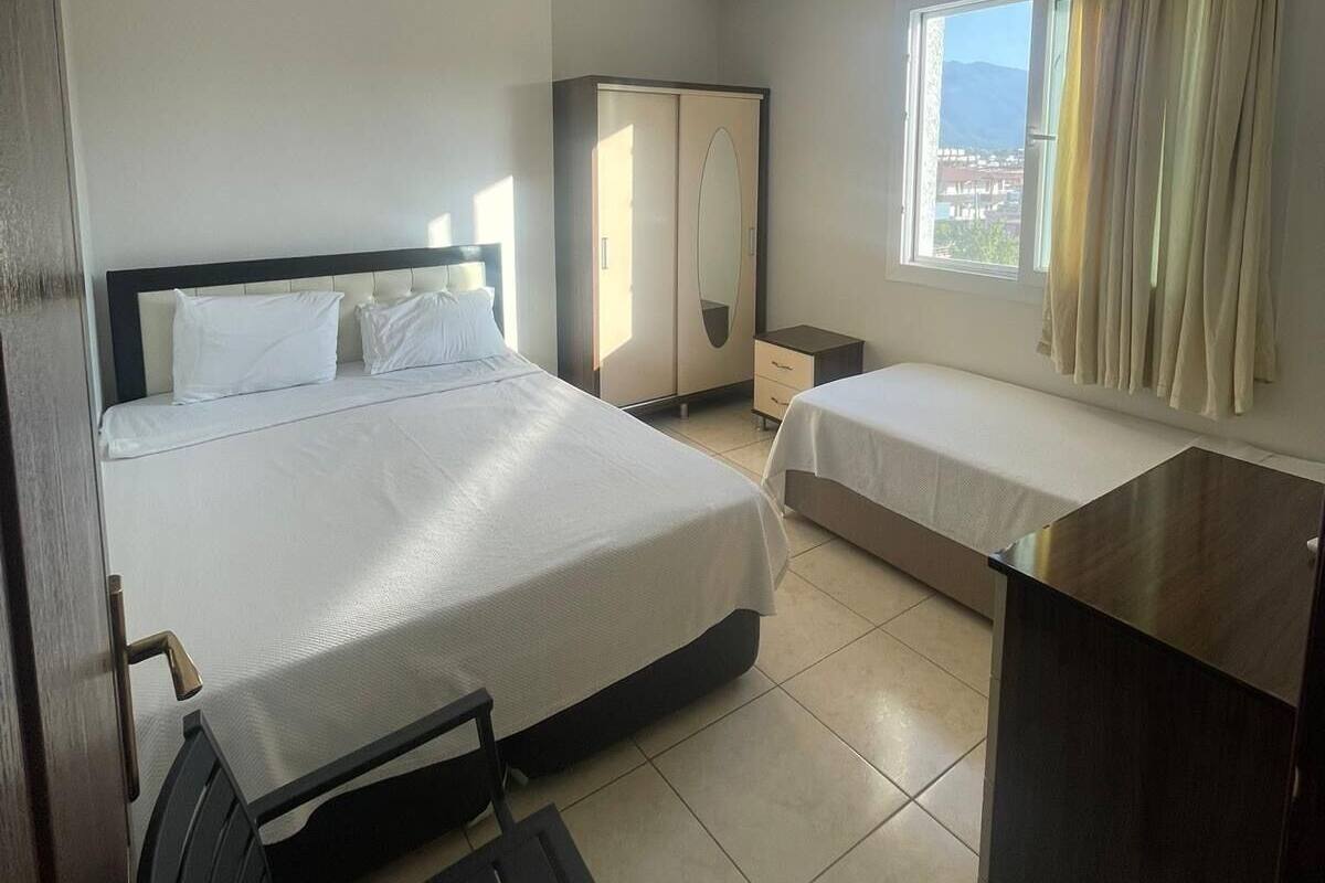 Habitación de hotel con una cama grande, una cama más pequeña, un escritorio, una silla y un armario.