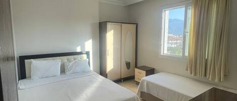 Habitación de hotel con una cama grande, una cama más pequeña, un escritorio, una silla y un armario.