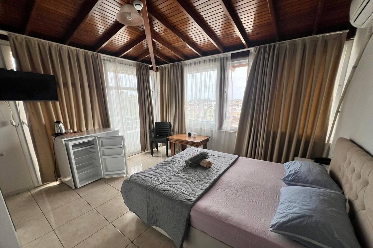 Un dormitorio con cama, escritorio, silla y televisor en la pared.