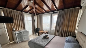 A bedroom with a bed, a desk, a chair, and a television on the wall.
