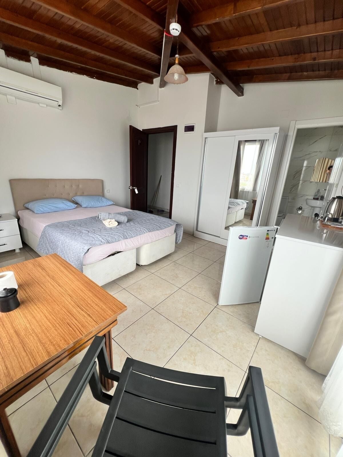 A bedroom with a bed, bedside table, and a small kitchenette.