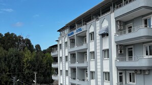 Un hôtel à plusieurs étages doté de balcons, de climatiseurs et d’un parking.