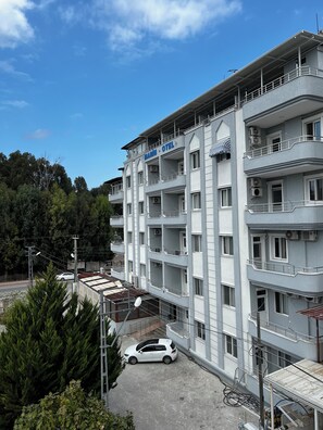 Un hotel de varios pisos con balcones, unidades de aire acondicionado y un estacionamiento.