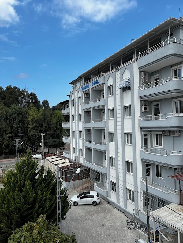 Un hotel de varios pisos con balcones, unidades de aire acondicionado y un estacionamiento.