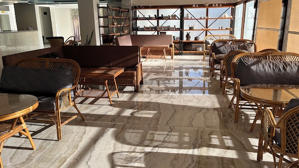 A spacious lounge area with a marble floor, wicker furniture, and a large window providing natural light.