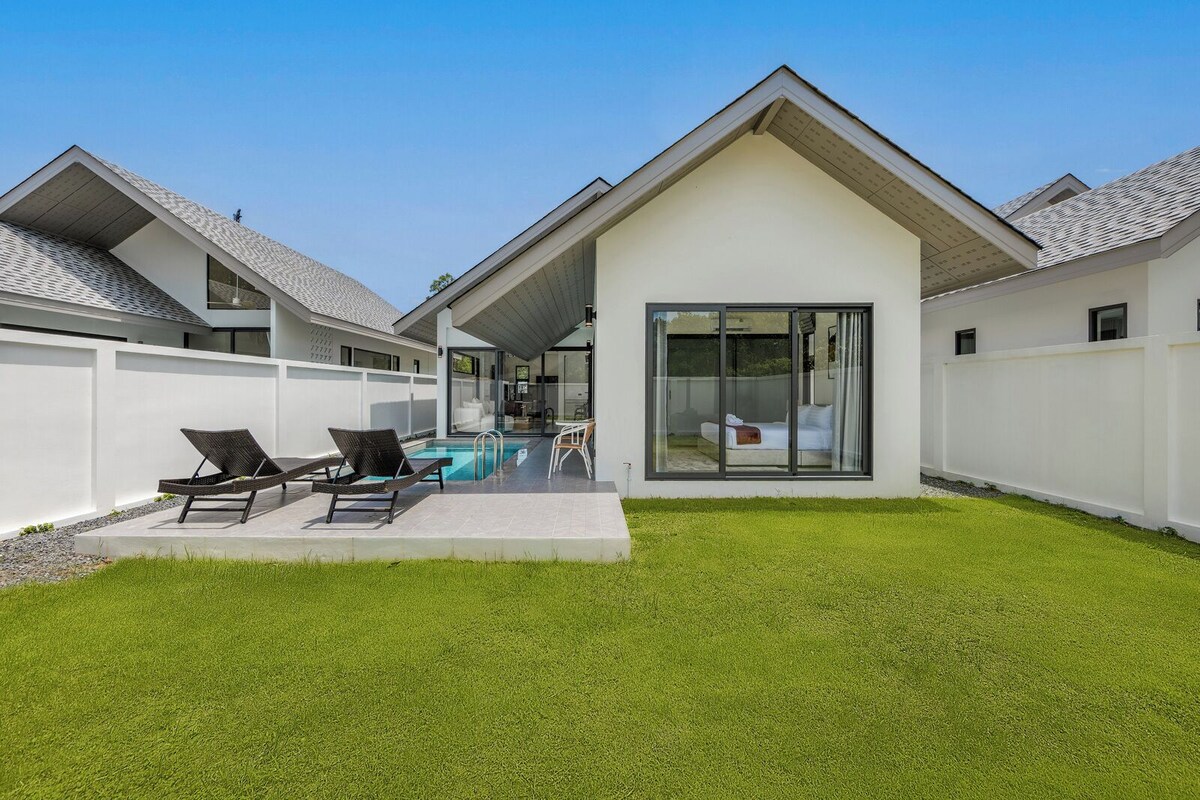 Una casa moderna con piscina, un porche cubierto y un césped bien cuidado.