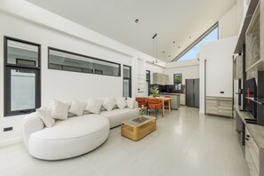 A modern living room with a sofa, coffee table, and dining area. - Akara Pool Villas Phuket by TropicLook  (Tambon Sa Khu)