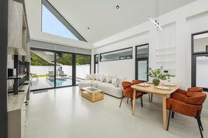 A modern living space with a dining area, a sofa, and a pool view. - Akara Pool Villas Phuket by TropicLook  (Tambon Sa Khu)