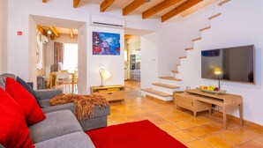 Ein Wohnzimmer mit Sofa, Fernseher, einer Holztreppe und einem Bild an der Wand.