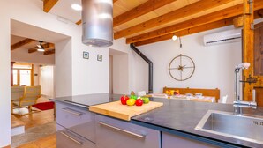 Eine moderne Küche mit Holzboden, einer zentralen Kochinsel mit Schneidebrett und einem Spülbecken.