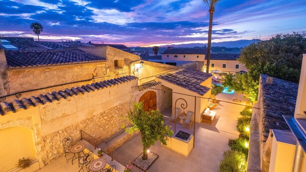A courtyard with stone walls, a palm tree, outdoor seating, and a pool area. - CAS CATALÀ - DOBLE ECONOMY - Beautiful room in a boutique hotel with shared pool and free (Sineu)
