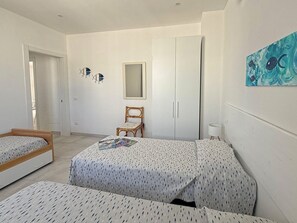 Ein Schlafzimmer mit zwei Betten, einem Kleiderschrank, einem Stuhl und einem Bild an der Wand.