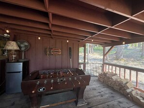 Ein Raum mit Holzboden, einer Kicker-Tischfußballmaschine, einem alten Ventilator und einem kleinen Kühlschrank.