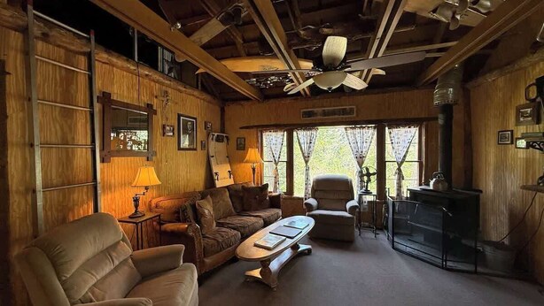 L’intérieur chaleureux d’un chalet avec un canapé, un fauteuil et une cheminée.