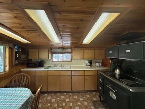 A compact kitchen with wooden cabinets, a microwave, a coffee maker, and a stove.