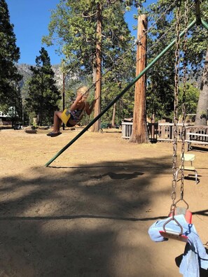 A playground with swings and a dirt ground.