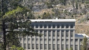 Un grand bâtiment à la façade symétrique, doté de nombreuses fenêtres et surmonté d’un toit plat.