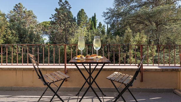 An outdoor dining area with a table set for two, featuring two glasses of white wine, a plate of food, and a bicycle parked in the background. - Camilluccia Quiet Corner (Roma)