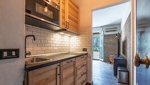 A kitchen with wooden cabinets, a stainless steel sink, and a brick backsplash. - Camilluccia Quiet Corner (Roma)